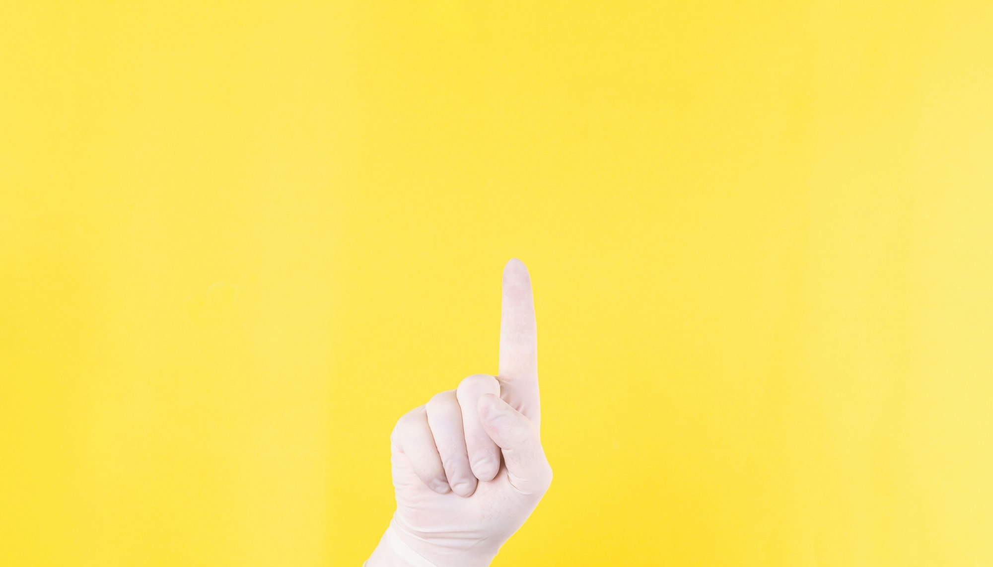 The close plan. Doctor's hand in a white medical glove on a yellow background shows up. The medicine. Place for an inscription. Advertising. Like. Medical gloves.