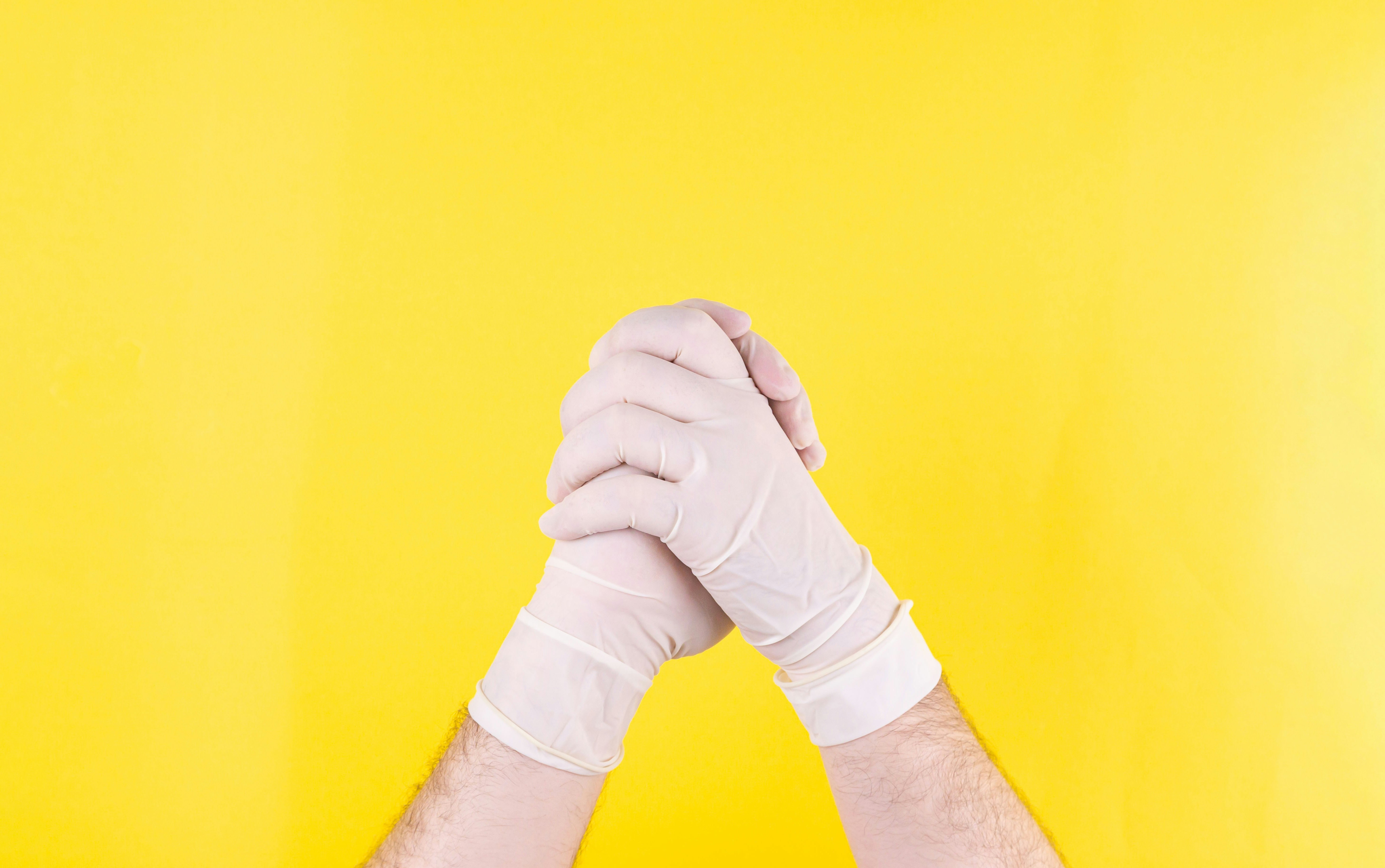 Handshake of doctors in white medical gloves on a yellow background. The medicine. Successful operation. Place for an inscription. Handshake. The close plan. Advertising. Covid 19.