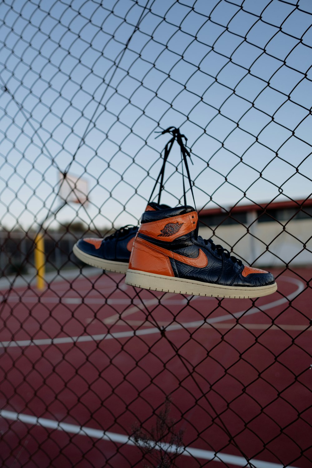 Chaussures de sport Nike orange et noir sur clôture à mailles losangées