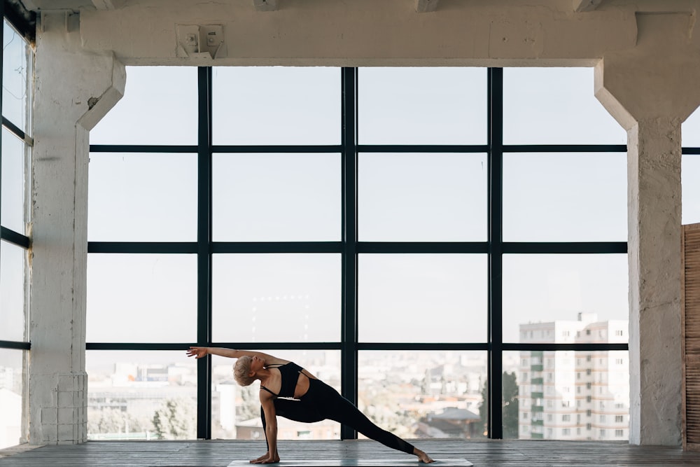 woman in black tank top and black pants standing near glass window during daytime