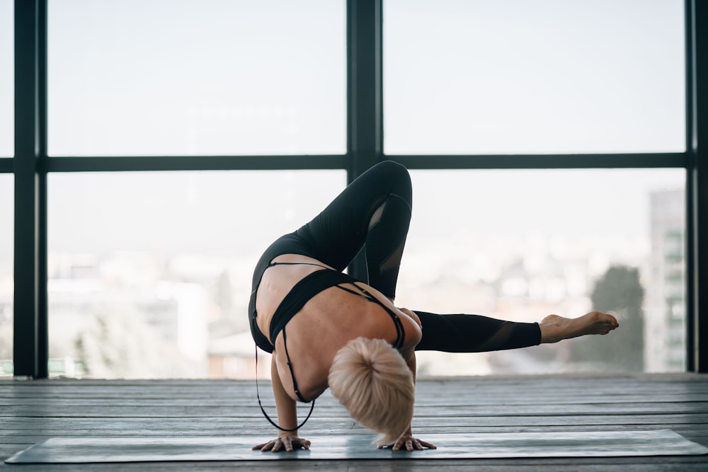 Frau in schwarzem Sport-BH und schwarzen Leggings beim Yoga