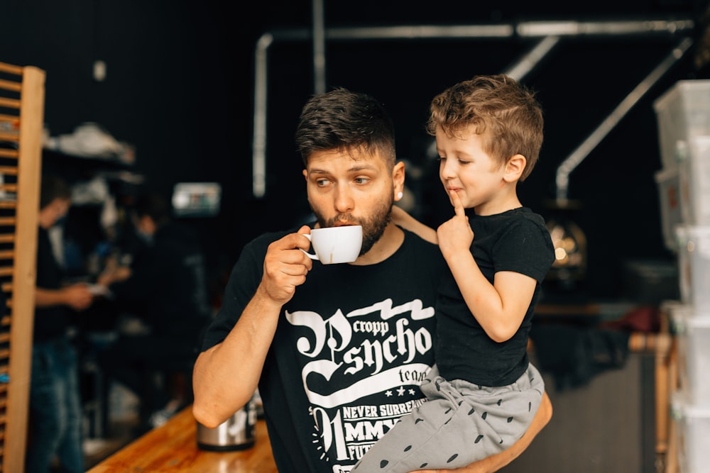 boy in black and white crew neck t-shirt drinking from white ceramic mug