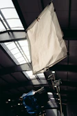 A sturdy c-stand holding a softbox diffuser on a film set.