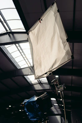 A sturdy c-stand holding a softbox diffuser on a film set.