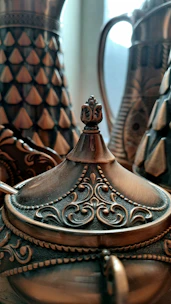 Close-up of a gleaming copper water jug with intricate hand-etched patterns