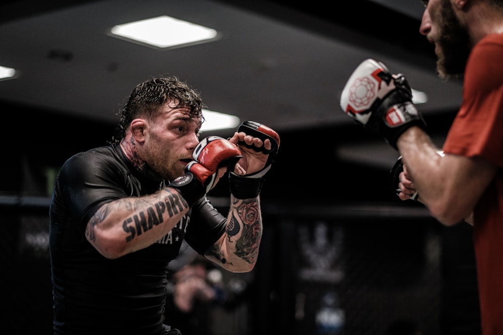 man in black crew neck t-shirt wearing brown boxing gloves