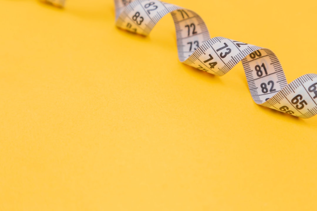 white tape measure on yellow surface, White measuring tape on a yellow background. Diet. Slimming. Obesity. Place for an inscription. Weight loss marathon. Advertising. Top view. The close plan.