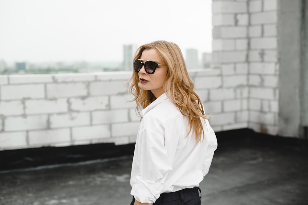 Femme en chemise blanche et pantalon noir portant des lunettes de soleil noires