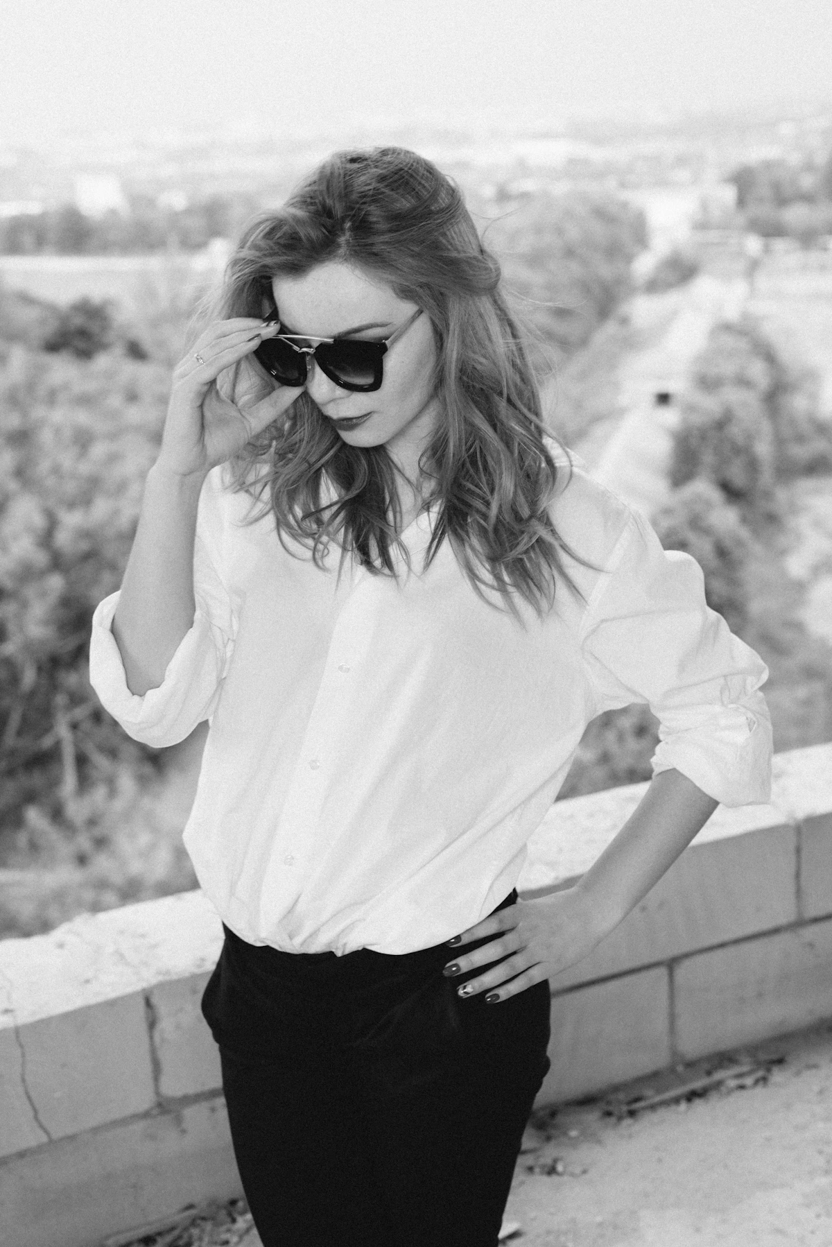 A woman in a cropped white shirt with high-waisted trousers
