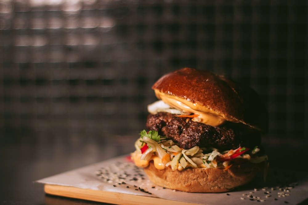 Burger mit Salat und Tomate auf weißem Schneidebrett