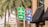 A collection of road signs located at a busy intersection, with an Interstate 95 sign, an airport directional sign, and other traffic instructions. Palm trees and a building with a Hertz sign are in the background.