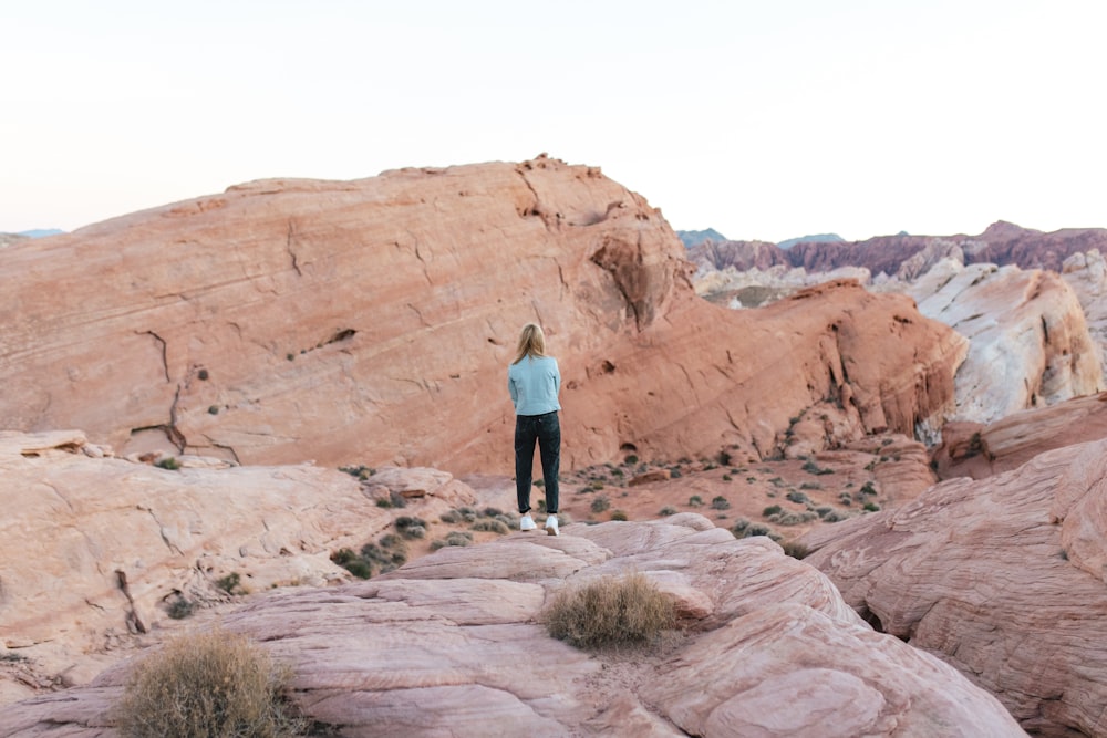 woman in blue jacket standing on brown rock formation during daytime