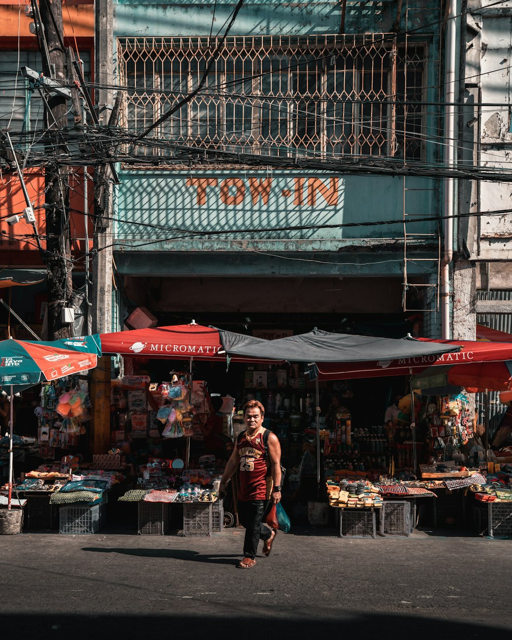 man in red jacket walking on sidewalk during daytime