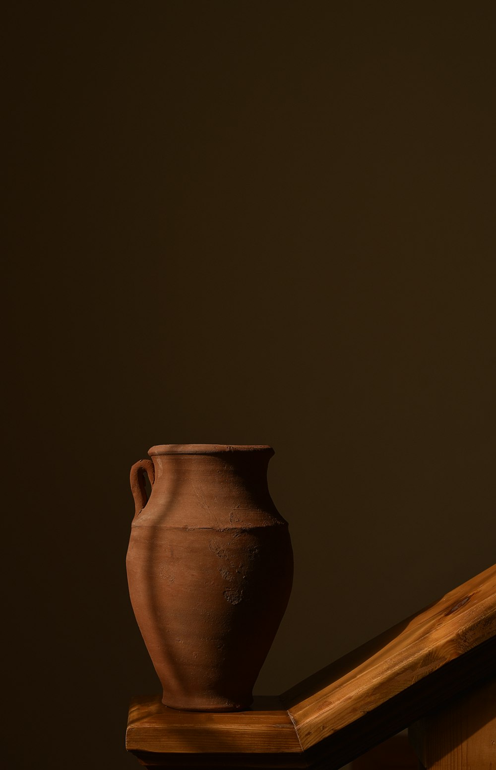 Jarrón de cerámica marrón sobre mesa de madera marrón