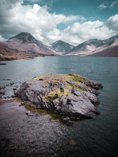 A happy group of tourists standing beside a serene loch with mountains in the background.
