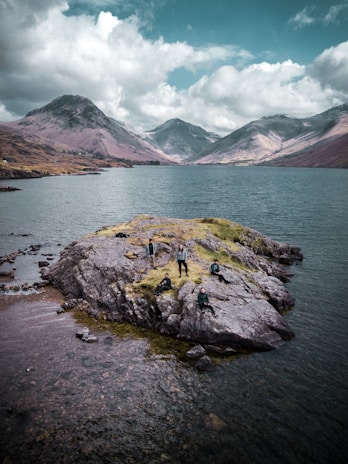 A happy group of tourists standing beside a serene loch with mountains in the background.
