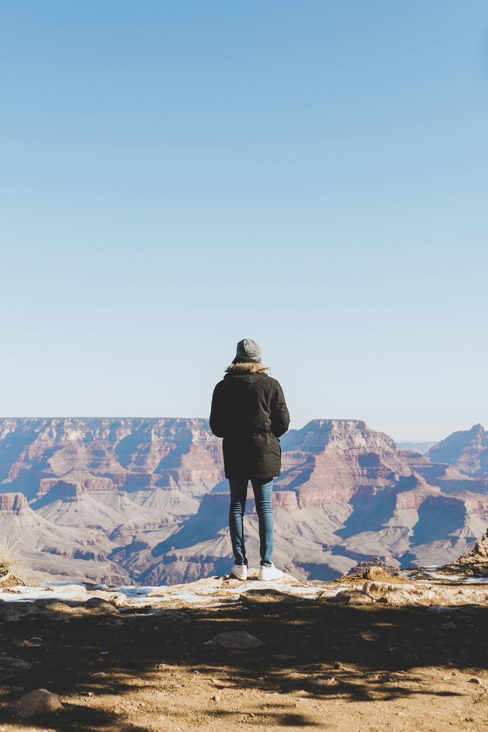 man in black jacket standing on rock formation during daytime