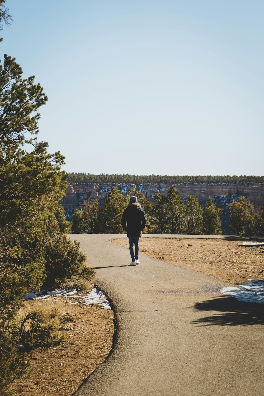 man in black jacket walking on gray concrete road during daytime