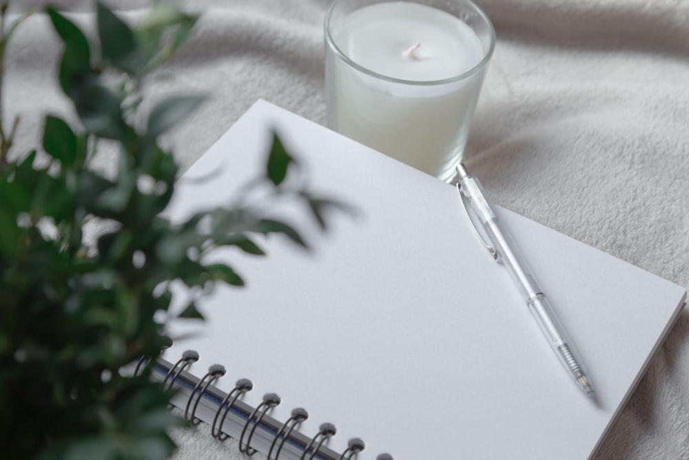clear drinking glass with white liquid on white spiral notebook