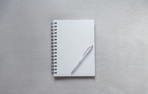 white notebook with pen on top