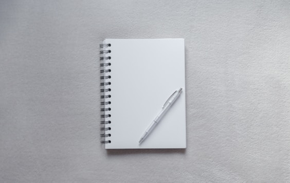 white notebook with pen on top