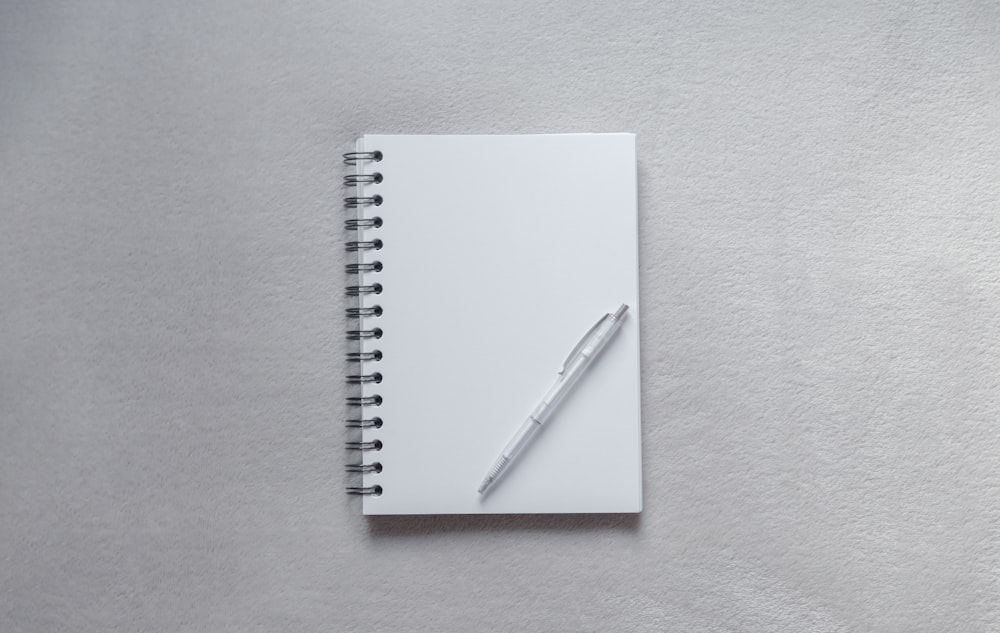 quaderno bianco con penna in cima