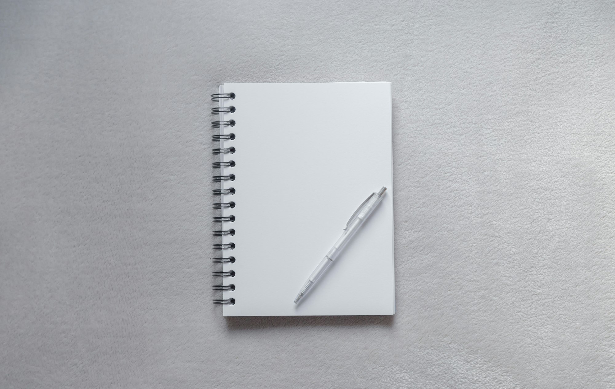 A school, office notebook with a white pen lies on a grey table