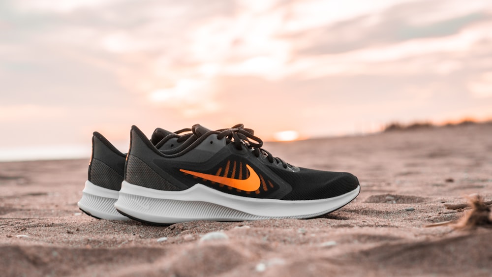 black and white nike athletic shoes on brown sand