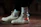 A pair of off-white high-top sneakers with a distinctive red and black design on the side, worn with white socks featuring a black logo. The shoes are on a brown surface, and the lighting creates a moody and stylish atmosphere.