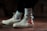 A pair of off-white high-top sneakers with a distinctive red and black design on the side, worn with white socks featuring a black logo. The shoes are on a brown surface, and the lighting creates a moody and stylish atmosphere.