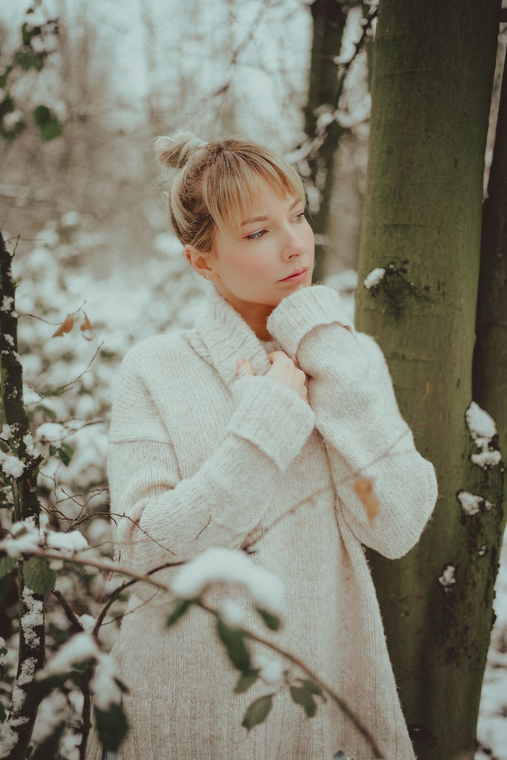 girl in white sweater standing beside tree
