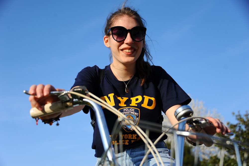 mulher na camiseta preta e amarela do pescoço da tripulação que anda de bicicleta durante o dia
