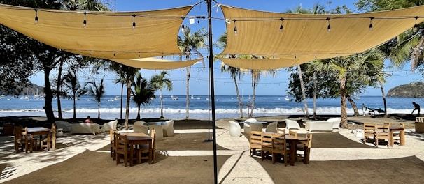 An outdoor dining area with sunny tables and beach views.