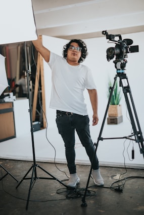 man in white crew neck t-shirt and black denim jeans standing near camera