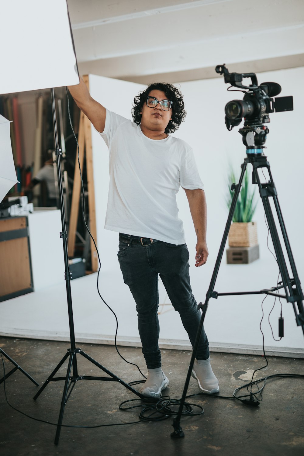 man in white crew neck t-shirt and black denim jeans standing near camera