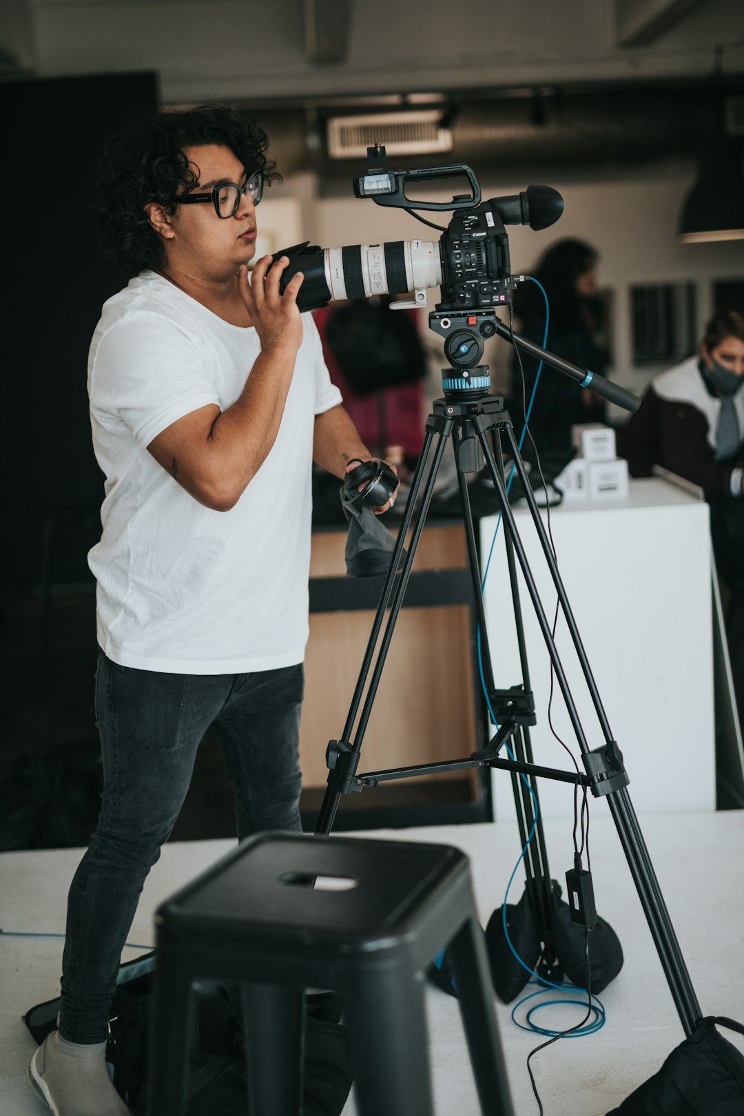 man in white t-shirt and blue denim jeans holding black dslr camera