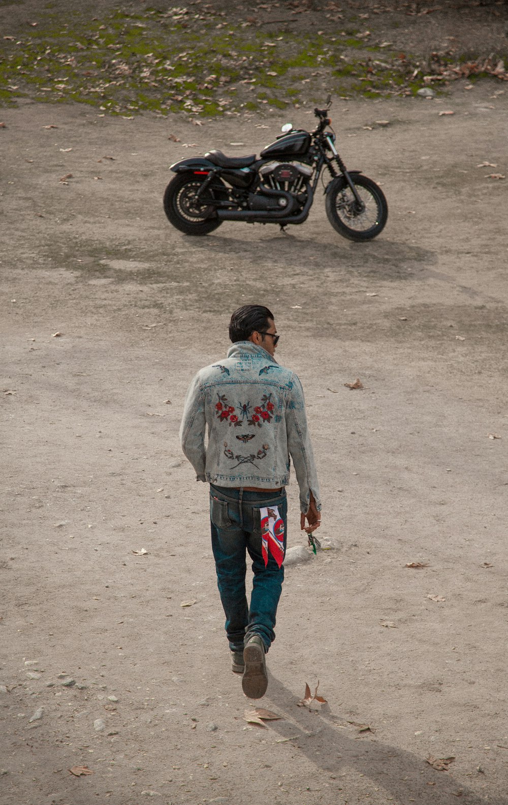 man in gray hoodie standing beside black motorcycle during daytime