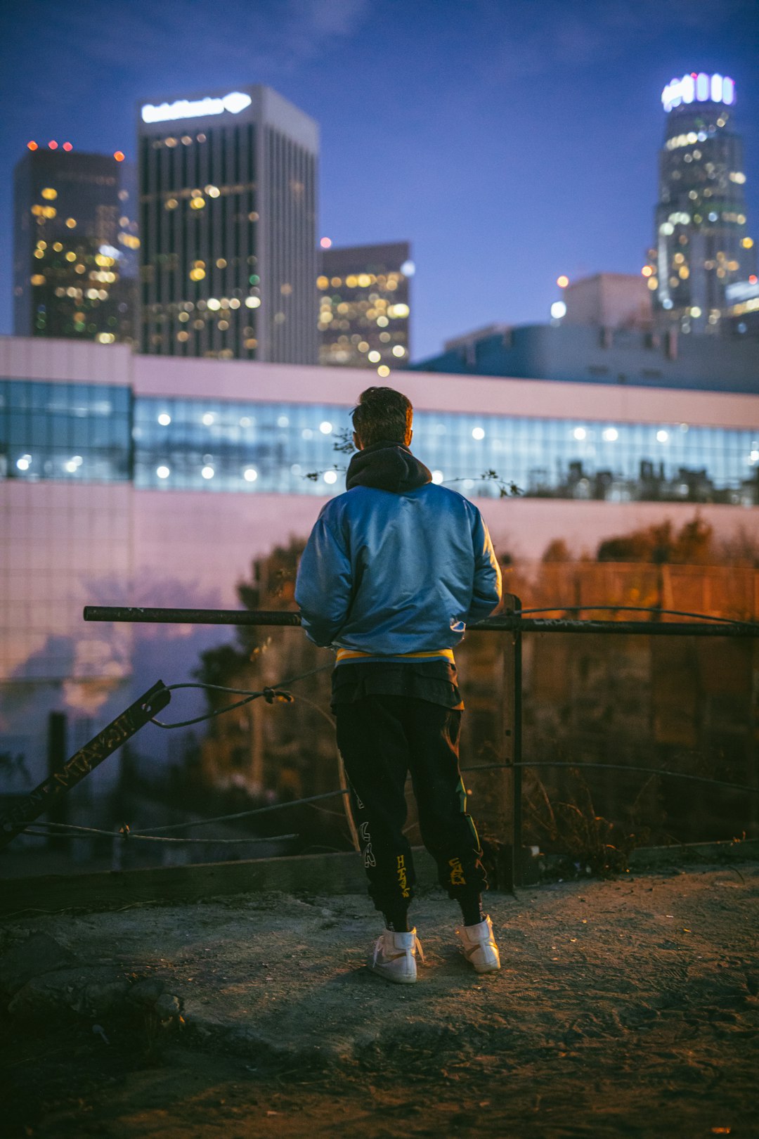 man in blue jacket standing on top of building during night time
