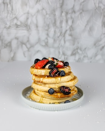 Whole grain pancakes stacked with berries and honey.