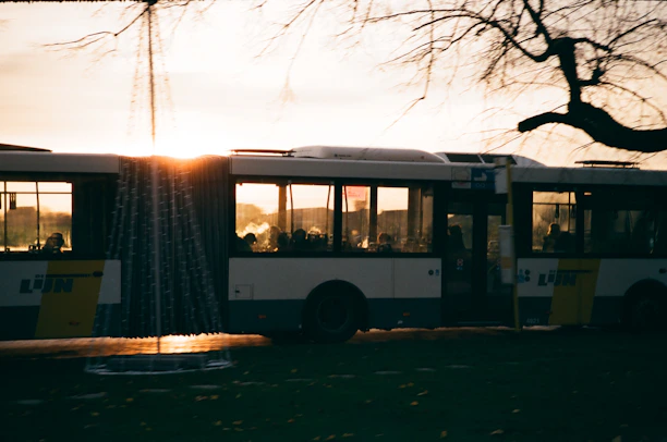 A modern bus from Vialume driving through a city street during sunrise.