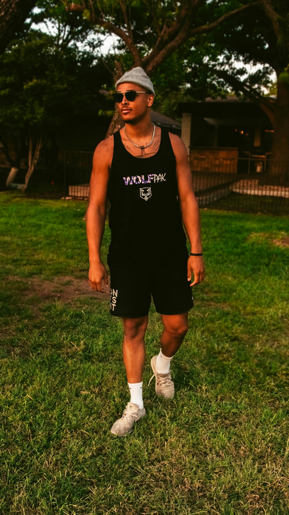man in black tank top and shorts standing on green grass field