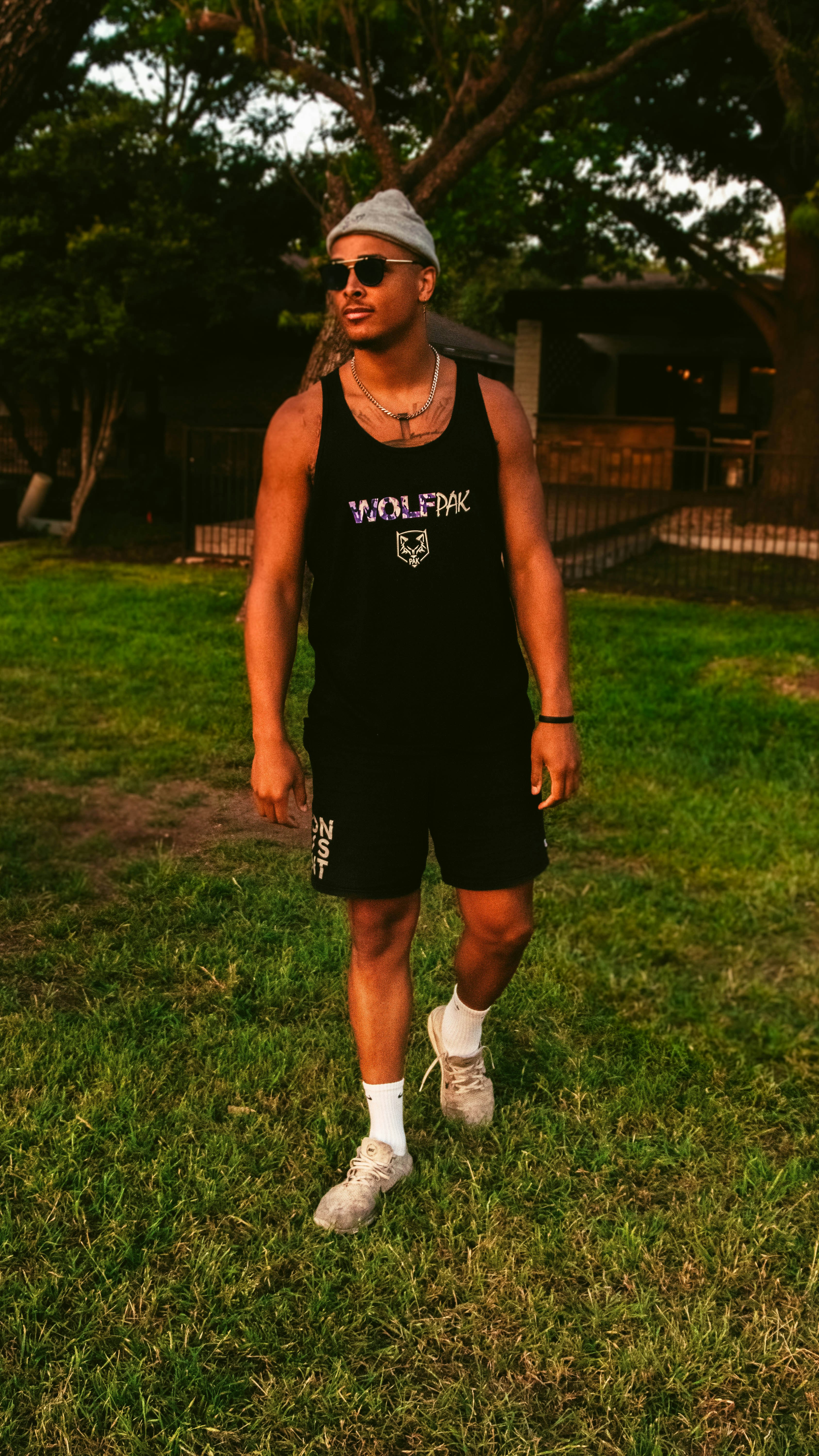 man in black tank top and shorts standing on green grass field