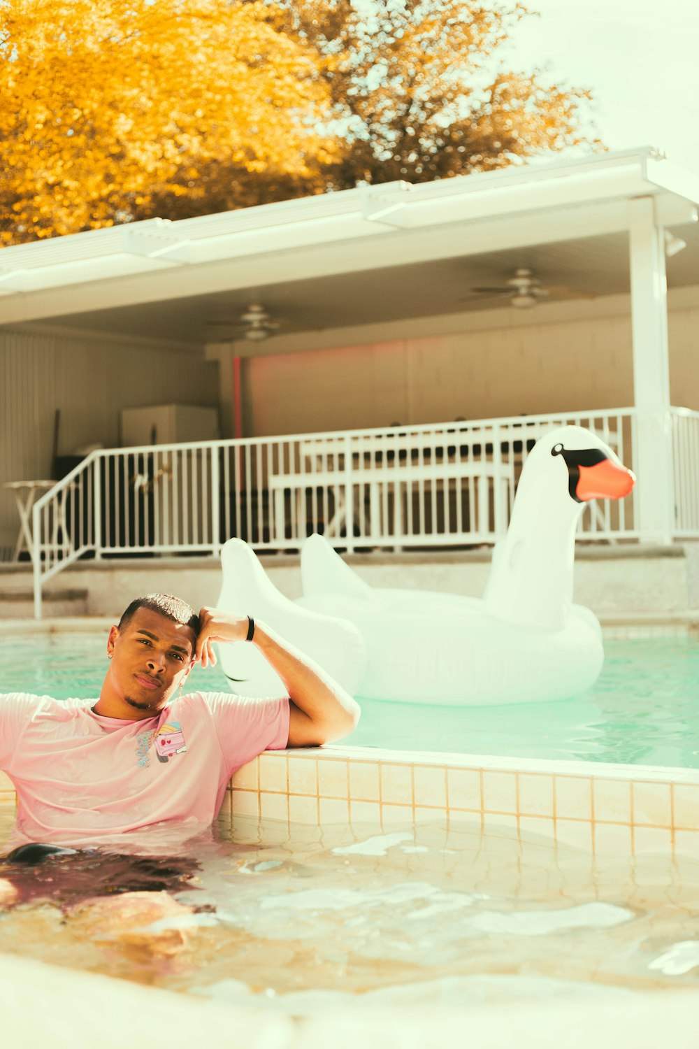 fille en chemise rose couchée sur un cygne gonflable blanc sur la piscine pendant la journée