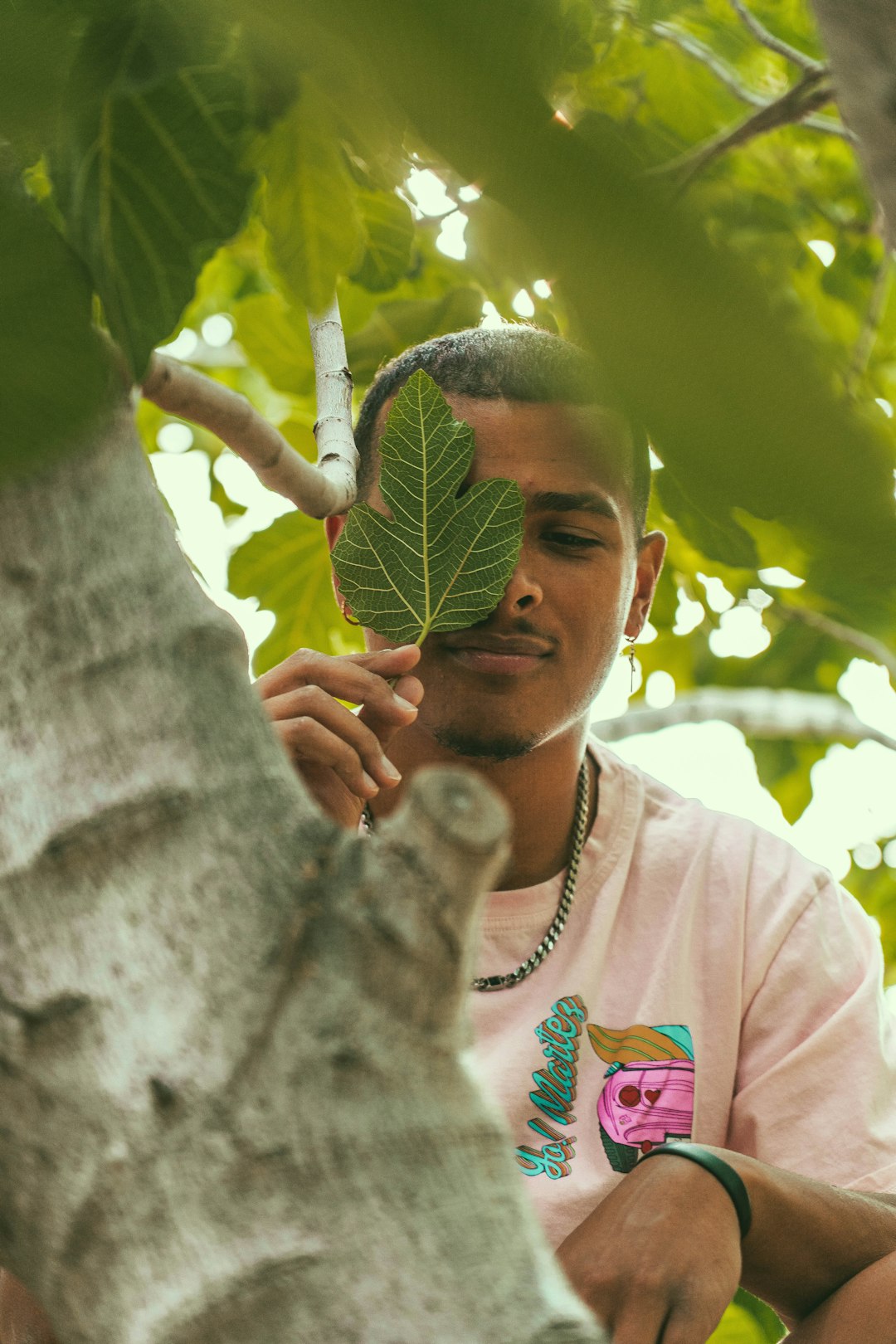 man in white crew neck t-shirt holding green leaf