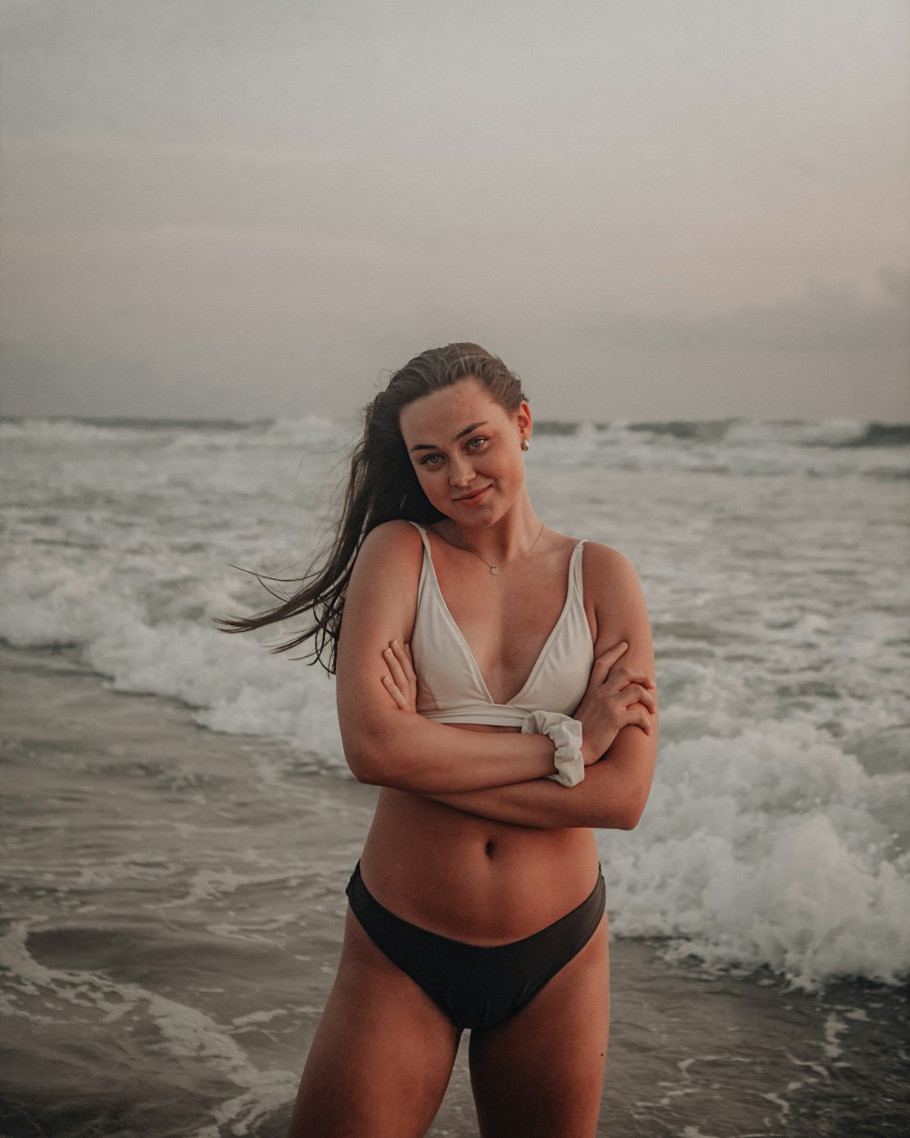 woman in white bikini top and black panty standing on beach during daytime