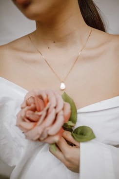 woman in white dress holding pink rose