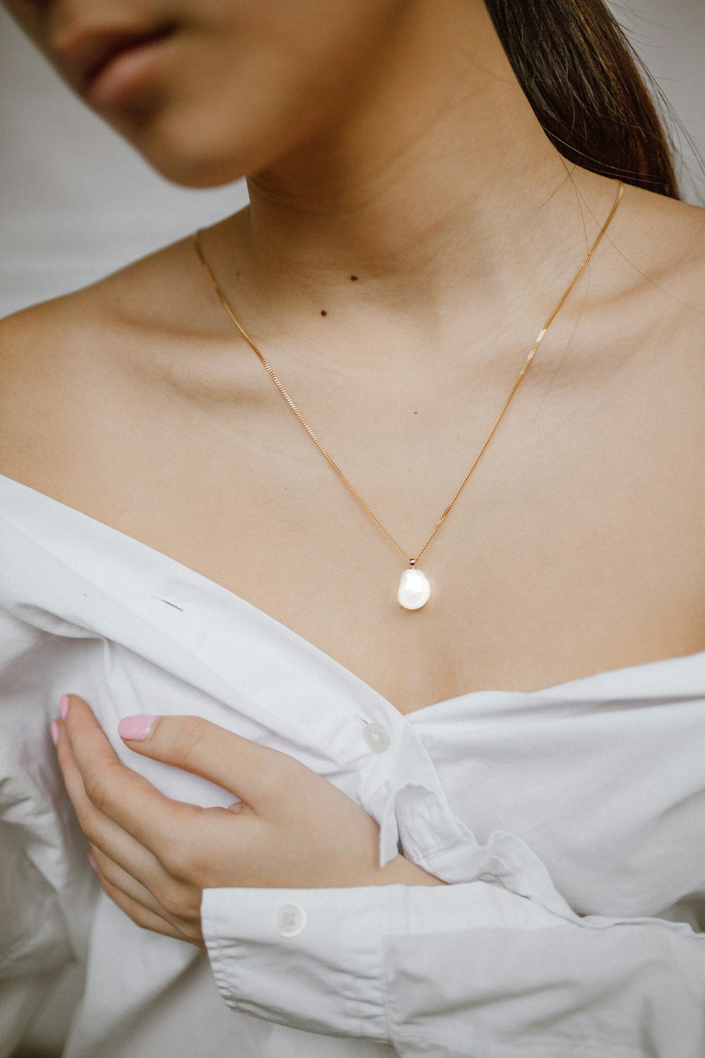 Mujer en camisa blanca abotonada con collar de oro