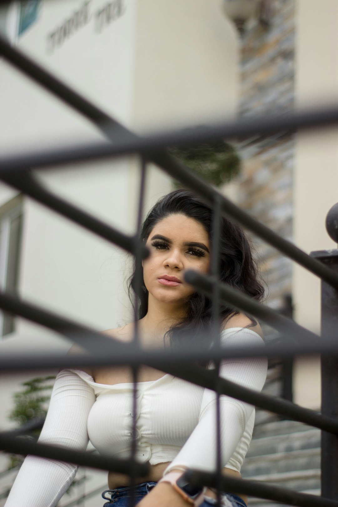 woman in white long sleeve shirt standing near black metal fence during daytime