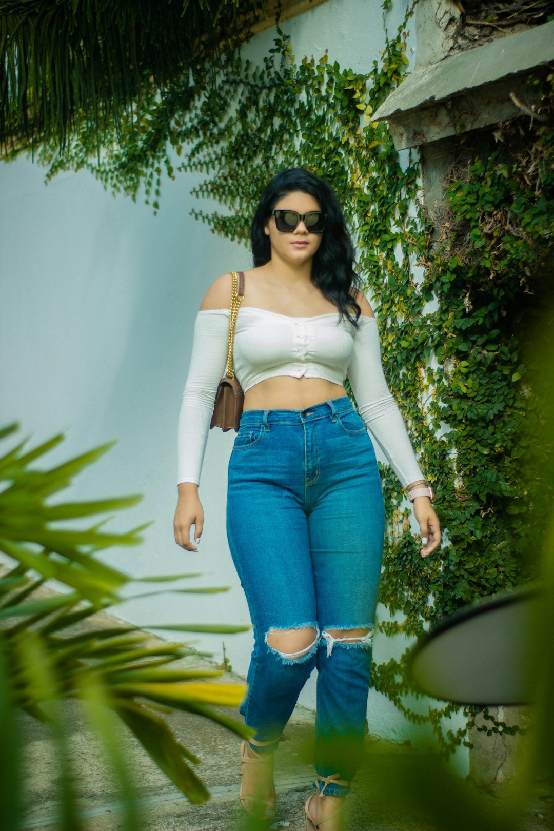 woman in white tank top and blue denim jeans wearing black sunglasses