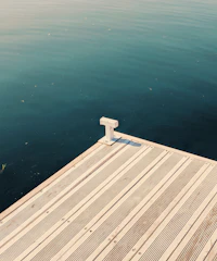 A sturdy dock extending over calm blue waters with a luxury boat moored.